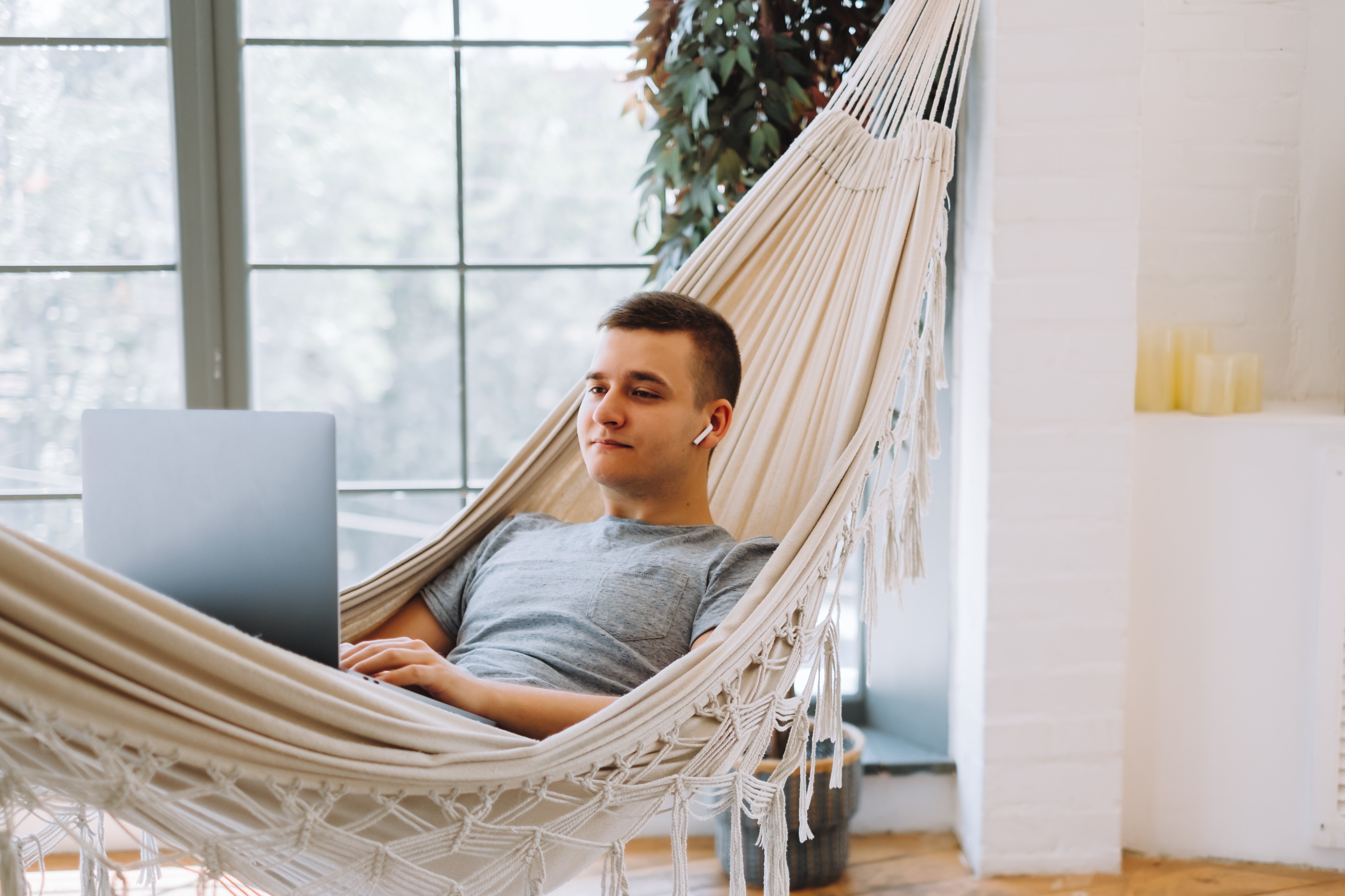 Businessman works from home while laying in a hammock