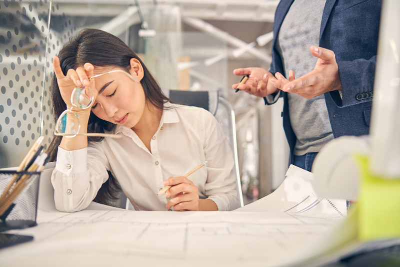 Tired woman rests her head on her arm while working at her desk
